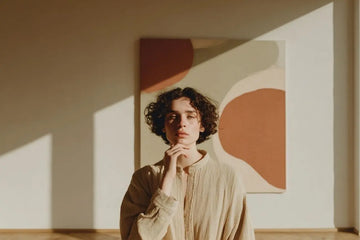 Frau betrachtet abstrakte Kunst in modernem Wohnzimmer mit natürlichem Licht und Erdtönen